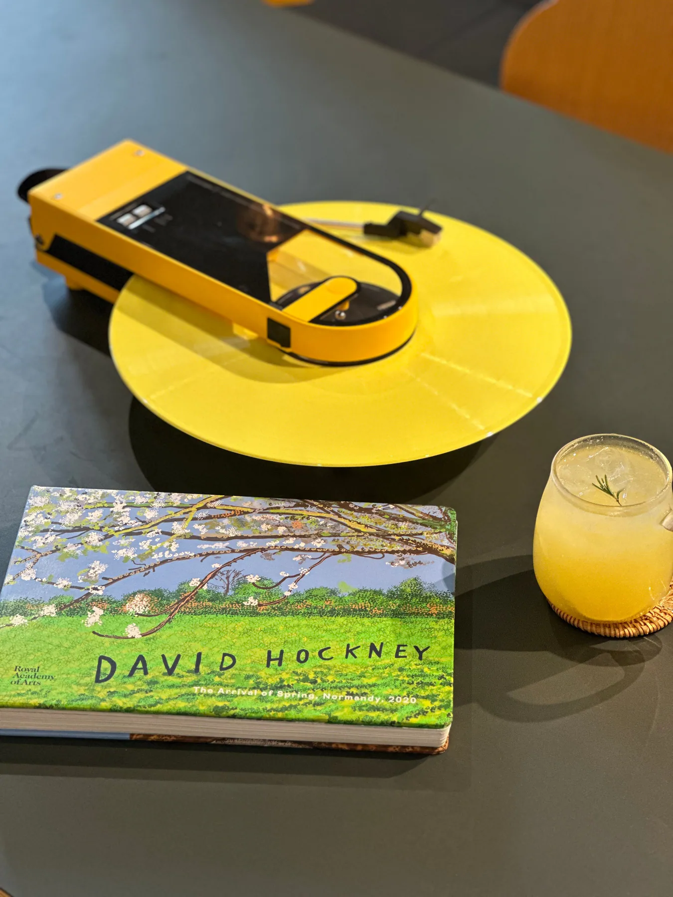 黄色いポータブルレコードプレーヤーと画集、グラスの飲み物